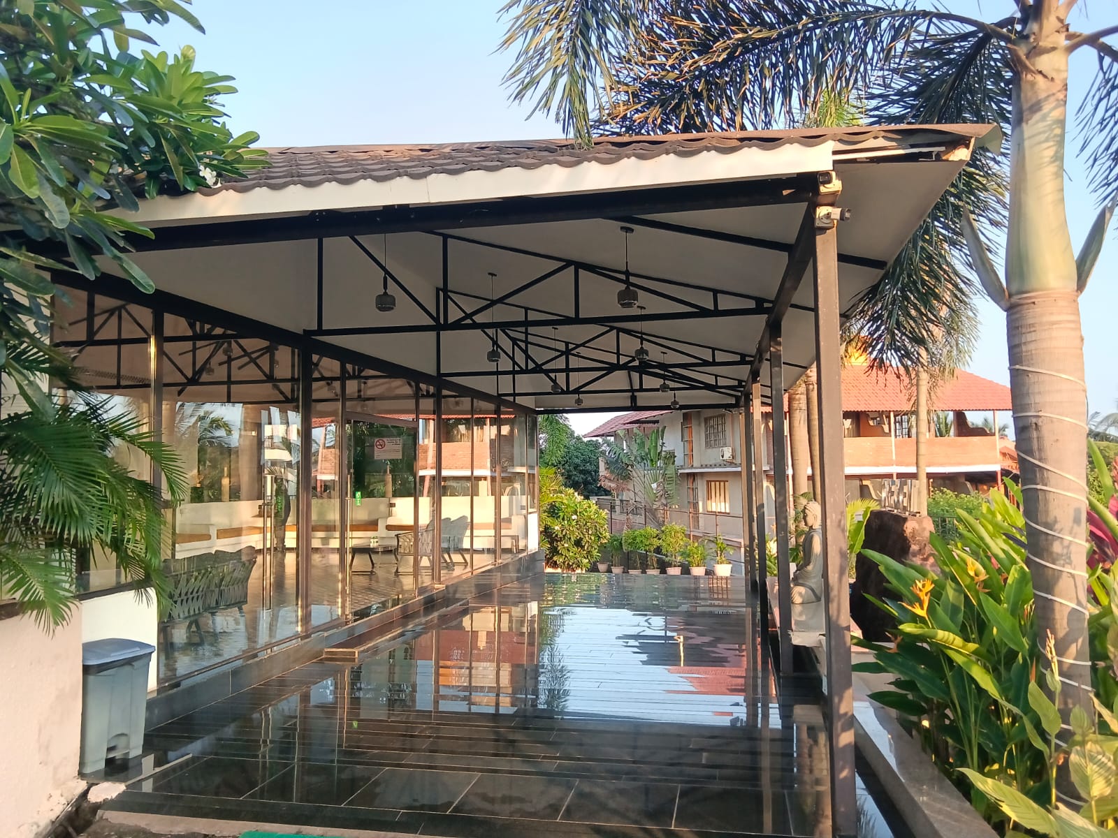 Glazed pavilion and wet stone walkway framed by palms